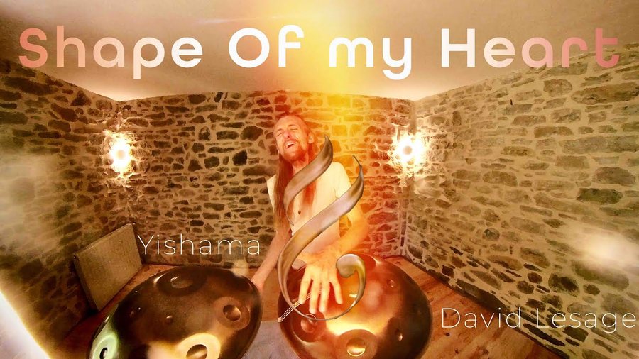 Deux handpans acoustiques en bronze au premier plan devant un mur de pierre éclairé par deux appliques, l’artiste assis derrière ; incrustations « Shape Of my Heart », « Yishama » et « David Lesage ».