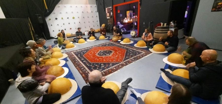 Une quinzaine de participants assis en cercle, chacun derriere sa calebasse posee sur un tapis